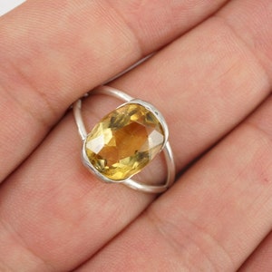May include: A silver ring with a large, oval-shaped, yellow gemstone.