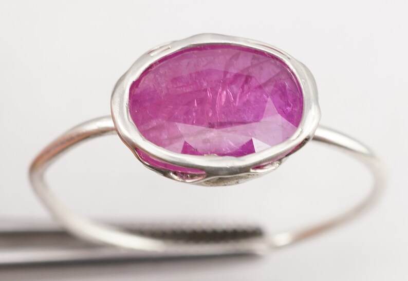 Op de afbeelding: Een zilveren ring met een grote ovale roze edelsteen gezet in een delicate zilveren zetting.