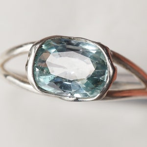 May include: A silver ring with a light blue oval gemstone set in a bezel setting.