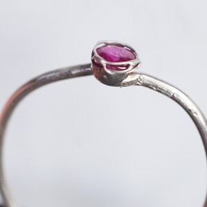 May include: A silver ring with a pink gemstone set in a delicate, openwork setting.
