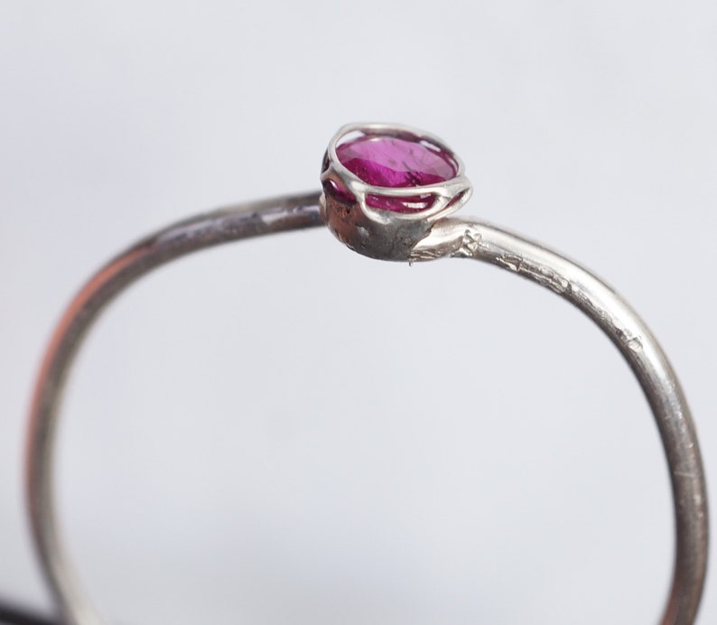 May include: A silver ring with a pink gemstone set in a delicate, openwork setting.