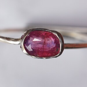 May include: A silver ring with a pink oval gemstone set in a textured bezel.