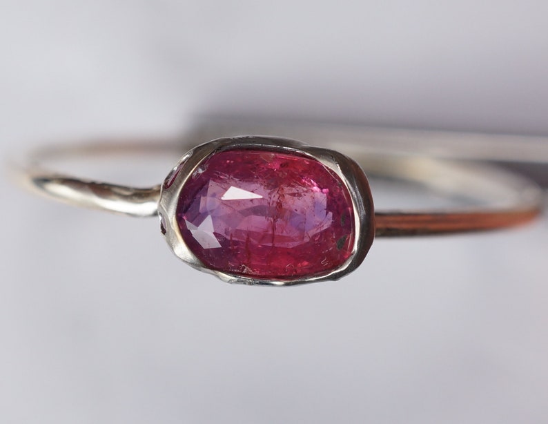 May include: A silver ring with a pink oval gemstone set in a textured bezel.