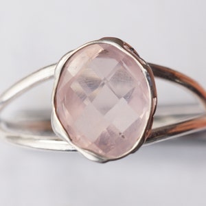 Puede incluir: Un anillo de plata con una gran piedra de cuarzo rosa ovalada facetada.