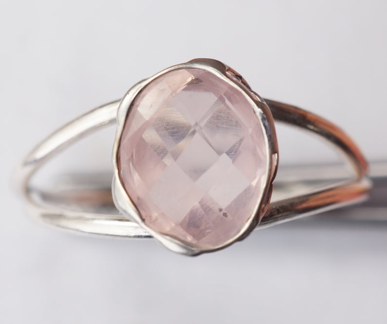 Puede incluir: Un anillo de plata con una gran piedra de cuarzo rosa ovalada facetada.