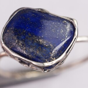 Puede incluir: Un anillo de plata con una piedra grande de lapisl&aacute;zuli azul oscuro de forma irregular engastada en un engaste de plata.