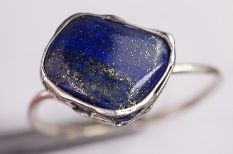 Puede incluir: Un anillo de plata con una piedra grande de lapisl&aacute;zuli azul oscuro de forma irregular engastada en un engaste de plata.
