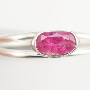 May include: A silver ring with a pink oval-shaped gemstone set in a bezel setting.