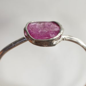 Op de afbeelding: Een zilveren ring met een roze, gefacetteerde edelsteen in een bezel-setting.