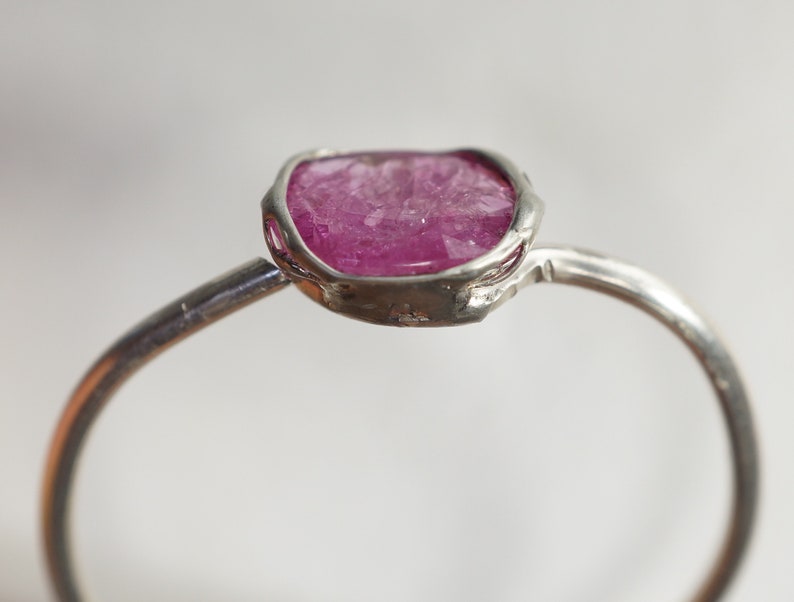 Op de afbeelding: Een zilveren ring met een roze, gefacetteerde edelsteen in een bezel-setting.
