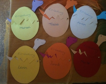 May include: Six colorful dinosaur egg invitations with the names Michael, Tobias, Anton, Levin, Yannick, and Merle written on them.