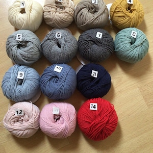 May include: Fourteen balls of yarn in various colors, including white, beige, gray, blue, green, yellow, pink, and red. Each ball is numbered 1 through 14.