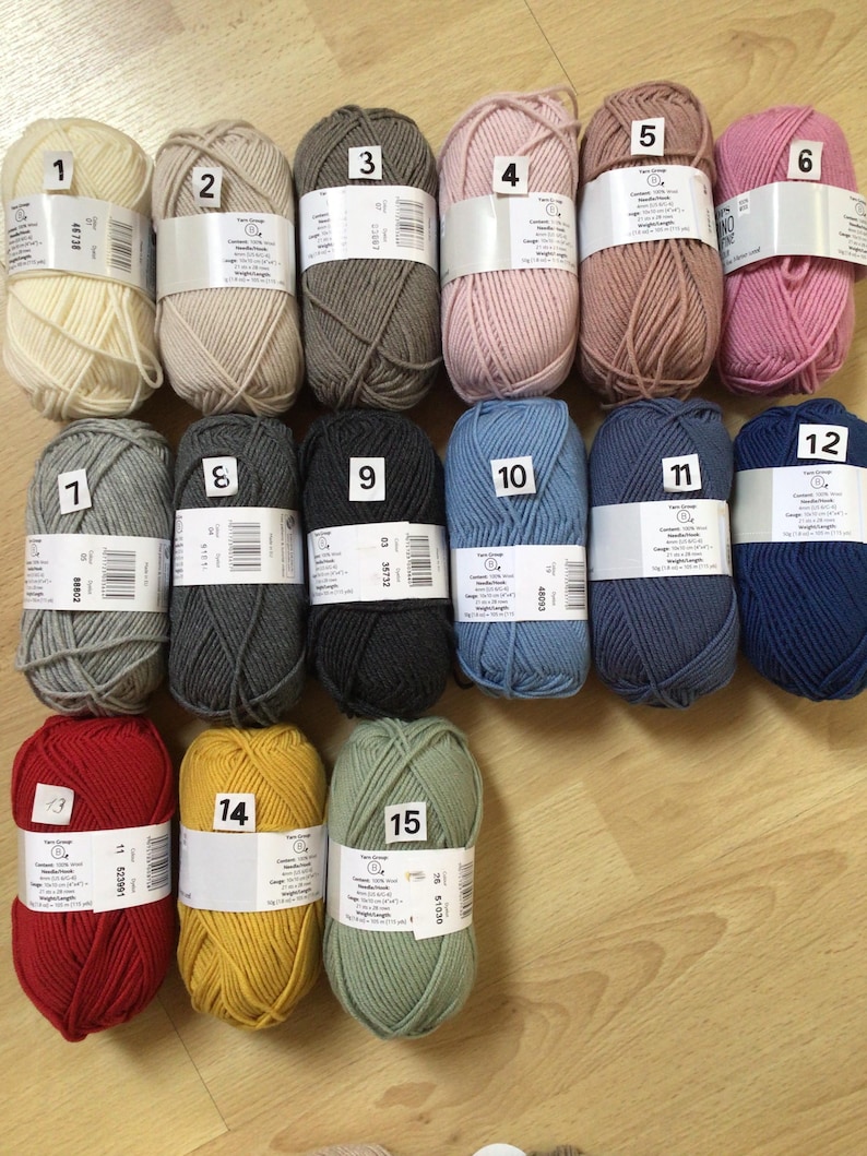 May include: A collection of 15 balls of yarn in various colors, including white, beige, gray, pink, red, yellow, and green. Each ball is labeled with a number from 1 to 15.