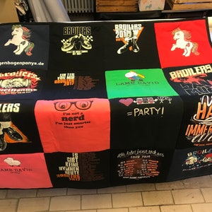 Könnte beinhalten: Eine schwarz-weiße Quiltdecke aus T-Shirts mit verschiedenen Designs und Texten. Die Quiltdecke zeigt eine Vielzahl von Farben, darunter Rot, Grün, Pink und Orange. Der Text auf der Quiltdecke beinhaltet die Wörter "Broilers", "Lamb David", "Party" und "Wir Haben Immer Noch".