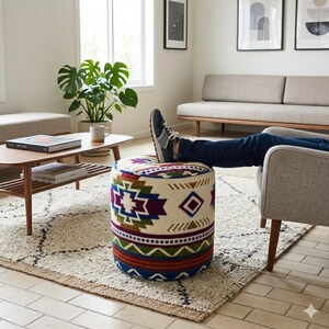 Könnte beinhalten: Ein runder Hocker mit einem geometrischen Muster in Blau, Lila, Grün und Rot auf cremefarbenem Grund. Der Hocker steht auf einem gemusterten Teppich in einem Wohnzimmer.