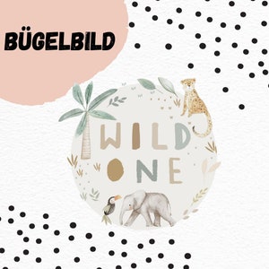 Puede incluir: Un círculo blanco y beige con las palabras "WILD ONE" en diferentes colores. El círculo está rodeado de hojas verdes, una palmera, un tucán, un elefante y un guepardo. El fondo es blanco con lunares negros. El texto "BÜGELBILD" está en la esquina superior izquierda.