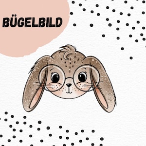 May include: Iron-on patch featuring a cute cartoon bunny wearing glasses. The bunny is brown with a white face and has large, round eyes. The text "BÜGELBILD" is in black letters on a pink background.