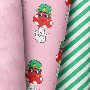 May include: Three fabric rolls: a solid pink, a pink with a repeating pattern of cartoon mushrooms wearing hats and glasses, and a green and white striped pattern. The mushroom pattern has red mushrooms with white spots.