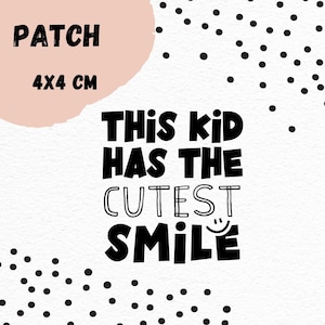 Könnte beinhalten: Schwarz-weißes Bügelbild mit dem Text "This kid has the cutest smile" und einem Smiley. Das Bügelbild ist 4x4 cm groß und befindet sich auf einem weißen Hintergrund mit schwarzen Punkten.