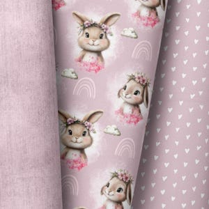 Può includere: Tessuto rosa con un motivo ripetitivo di conigli marroni che indossano corone di fiori. I conigli sono circondati da fiori rosa, nuvole e arcobaleni. Il tessuto è perfetto per progetti di artigianato, quilting e arredamento della casa.