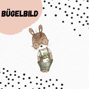 May include: Iron-on patch featuring a cute cartoon bunny wearing glasses and overalls with a clover on the pocket. The bunny is brown with a white shirt and green overalls. The background is white with black polka dots.