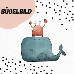 Può includere: Una balena blu con un occhio chiuso e un granchio rosso sopra. La balena ha una pinna caudale e una piccola pinna sulla schiena. Il granchio ha due grandi chele e due piccoli occhi. Lo sfondo è bianco con pois neri. Il testo "BÜGELBILD" è nell'angolo in alto a sinistra dell'immagine.