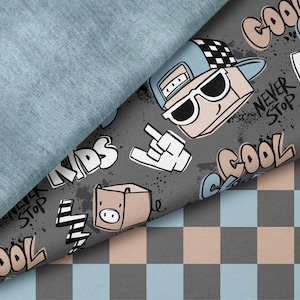 Peut inclure: Gros plan sur trois tissus différents. L'un est bleu clair uni, un autre est gris avec des graphiques de dessins animés et du texte, et le troisième est un motif à carreaux gris, bleu clair et beige. Le tissu gris porte les mots "COOL CLUB KIDS" et "NEVER STOP".