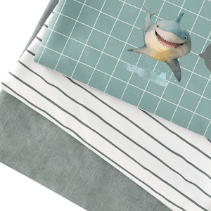 May include: A stack of three fabric swatches. The top swatch is teal blue with a white grid pattern and a cartoon shark with the word "HEY" in a speech bubble. The middle swatch is white with thin black stripes. The bottom swatch is a solid gray.