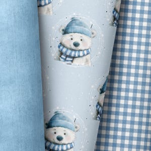 Könnte beinhalten: Ein blauer und weißer Stoff mit einem sich wiederholenden Muster eines Eisbären, der einen blauen Hut und einen Schal trägt. Der Bär ist von einem weißen Kreis mit Sternen umgeben.