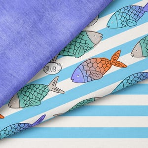 May include: A folded fabric featuring a solid purple section and a white section with light blue horizontal stripes. The striped fabric displays a repeating pattern of colorful fish in shades of blue, green, and orange, with speech bubbles containing the text BLUB.