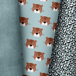 Könnte beinhalten: Ein blauer Stoff mit einem sich wiederholenden Muster aus braunen Leopardengesichtern. Der Stoff liegt neben einem schwarz-weißen Leopardenmusterstoff.