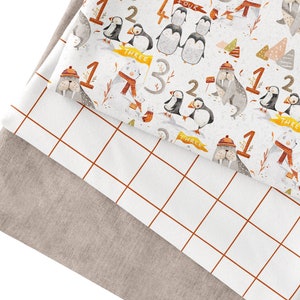May include: Three layers of fabric, including a light brown, white grid, and patterned top layer. The top layer has penguins, walruses, and polar bears with numbers and flags. Suitable for a baby or child.