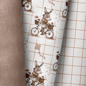 Könnte beinhalten: Ein weißer Hintergrund mit einem braunen Gittermuster. Ein Esel, der ein Fahrrad mit einem Korb voller Pilze fährt, wiederholt sich im gesamten Muster.