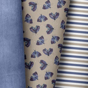 Könnte beinhalten: Ein beigefarbener Stoff mit einem sich wiederholenden Muster aus dunkelblauen Schmetterlingen mit einem Galaxie-Design. Der Stoff liegt neben einem blauen Jeansstoff und einem gestreiften Stoff mit abwechselnd beige und dunkelblauen Streifen.