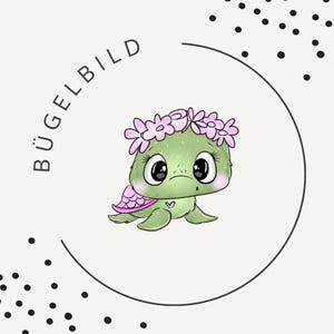 May include: A cute cartoon turtle with a green body, pink shell, and a floral crown. The turtle has large, expressive eyes and a small heart on its chest. The word "BÜGELBILD" is written in a semi-circle above the turtle.