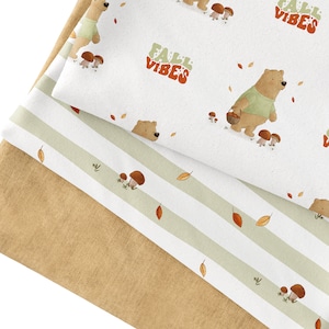 May include: Three fabric swatches, one with a brown background, one with a white background and green stripes, and one with a white background and a repeating pattern of bears, mushrooms, and the text "Fall Vibes".