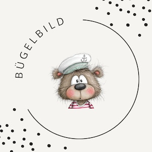 May include: A graphic illustration of a brown, furry bear wearing a white sailor hat with an anchor emblem and a red and white striped shirt. The text BÜGELBILD is printed in black along a circular border, surrounded by black polka dots.