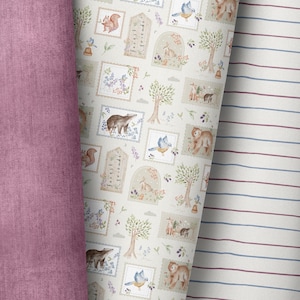 May include: A white fabric with a repeating pattern of woodland animals and plants. The pattern includes bears, squirrels, birds, trees, and flowers. The fabric is surrounded by two other fabrics, one pink and one striped.