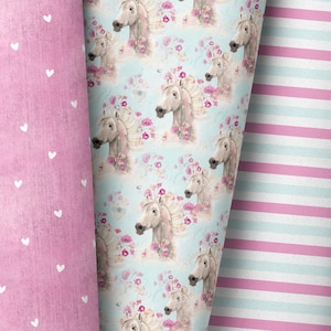 May include: Three rolls of decorative paper. One roll is pink with white hearts, another features a pattern of white horses with floral manes on a light blue background, and the third has pink and white stripes.