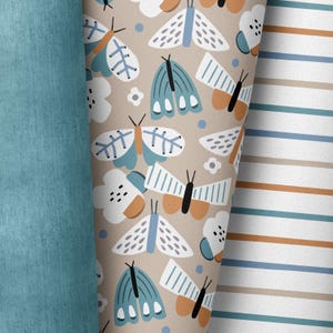 Könnte beinhalten: Ein beigefarbener Stoff mit einem sich wiederholenden Muster aus blauen und weißen Schmetterlingen. Die Schmetterlinge haben ein stilisiertes Design mit geometrischen Formen und sind vor einem Hintergrund aus kleinen weißen Blüten und braunen Punkten angeordnet.