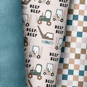 May include: A pink and white fabric with a repeating pattern of green toy trucks and the words "Beep Beep".