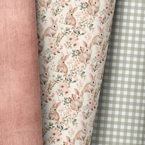 Può includere: Primo piano di tre tessuti diversi. Uno è di colore rosa cipria, il secondo è un motivo floreale con coniglietti e fiori, e il terzo è un motivo a quadretti verde e bianco. Il motivo floreale è il punto focale.