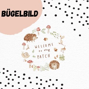 Può includere: Un'illustrazione stravagante con una ghirlanda di elementi autunnali: funghi, ghiande e ricci. Il testo "WELCOME to our PATCH" è all'interno della ghirlanda. La parola "BÜGELBILD" è in alto a sinistra, su sfondo rosa.