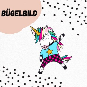 Puede incluir: Parche para planchar con un unicornio de dibujos animados que lleva una camisa azul con una estrella amarilla, pantalones a cuadros rosa y negros y un tatuaje de corazón en el brazo. El unicornio tiene una melena y una cola arcoíris. El texto "BÜGELBILD" está en la esquina superior izquierda de la imagen.