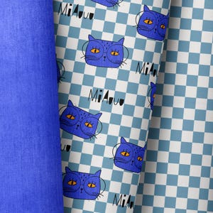 May include: Blue and white checked fabric with a repeating pattern of blue cats wearing glasses and the text "Miauu".