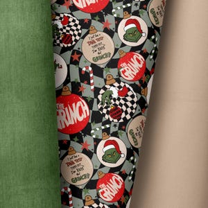 Könnte beinhalten: Ein schwarzer und grüner Weihnachtsstoff mit einem sich wiederholenden Muster aus Kugeln, Zuckerstangen, Sternen und dem Grinch. Die Kugeln sind rot, grün und weiß mit den Worten "The Grinch" und "I just had a DNA test turns out I'm 100% Grinch!" bedruckt.