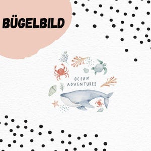 May include: A watercolour illustration of marine creatures, including a whale, crab, and turtle, with the text "Ocean Adventures." The design is set against a white background with black polka dots and the German text "BÜGELBILD" in the upper left corner.