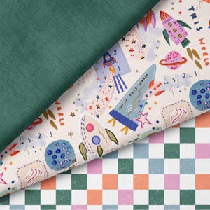 Könnte beinhalten: Ein Bild mit drei Stoffmustern. Die oberste Schicht ist einfarbig dunkelgrün. Die mittlere Schicht hat einen cremefarbenen Hintergrund mit Raketen, Planeten und Sternen. Die untere Schicht ist ein kariertes Muster in Rosa, Orange, Grün und Blau.