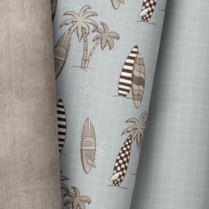 以下が含まれることがあります： 茶色とタンの色合いのサーフボードとヤシの木の繰り返し模様が特徴の薄い青色の生地。サーフボードには、ストライプや市松模様など、さまざまなデザインがあります。背景にはグリッドパターンがあります。