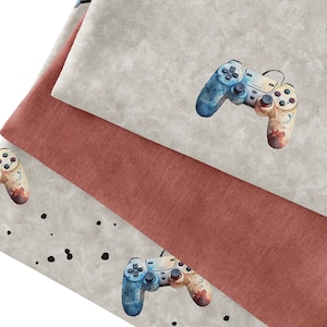 May include: Three fabric swatches with a watercolor-style design of a video game controller. The top swatch is a light gray with a blue and yellow controller. The middle swatch is a reddish-brown color. The bottom swatch is a light gray with a blue and yellow controller and black dots.